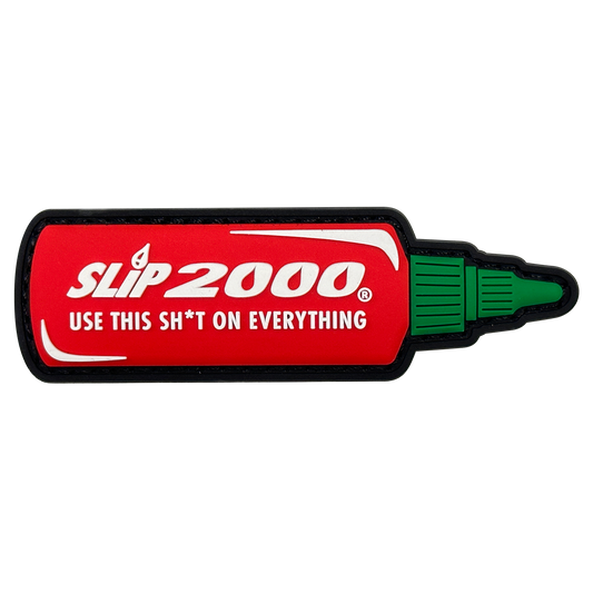 A PVC patch designed to look like a hot sauce bottle with the text 'SLIP 2000 USE THIS SH*T ON EVERYTHING' on a red background with the cap part of the design in green